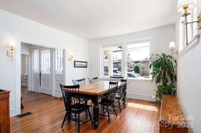 dining area featuring hardwood / wood-style flooring, baseboards, and visible vents
