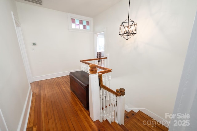 corridor with baseboards, an upstairs landing, a notable chandelier, and hardwood / wood-style floors