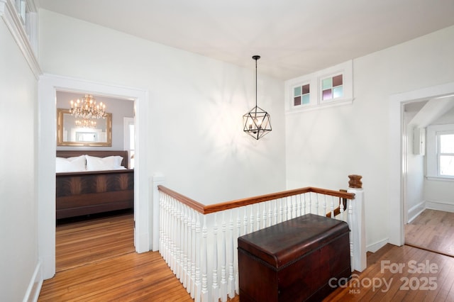 interior space with an upstairs landing, a notable chandelier, baseboards, and hardwood / wood-style flooring