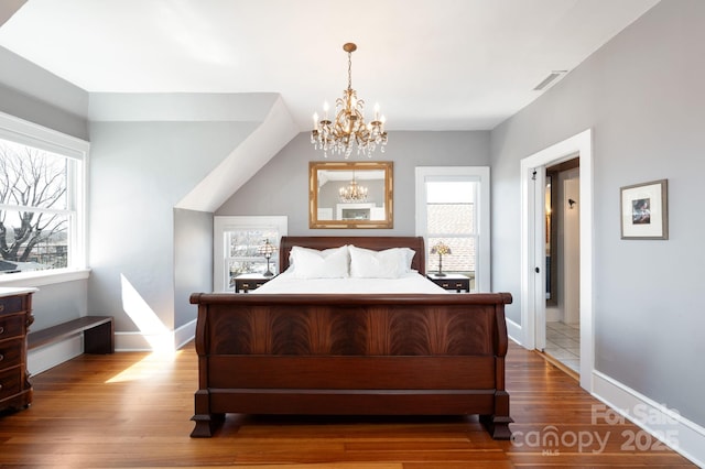 bedroom featuring multiple windows, a notable chandelier, wood finished floors, and visible vents