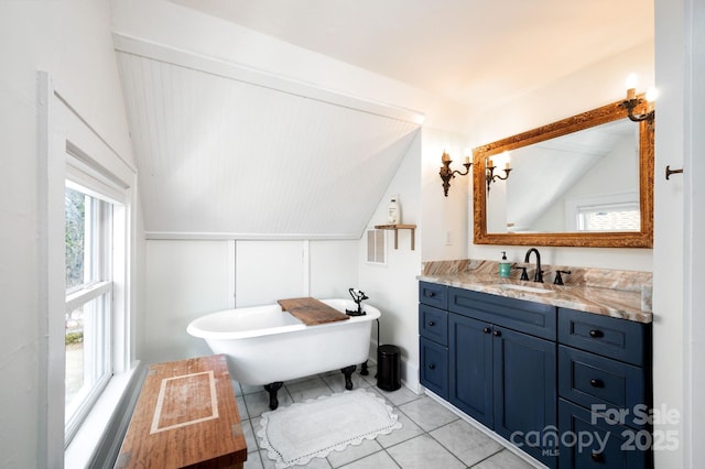 bathroom featuring vanity, lofted ceiling, a soaking tub, and tile patterned floors