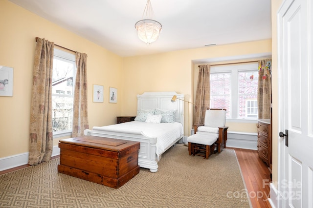 bedroom with visible vents, baseboards, and wood finished floors