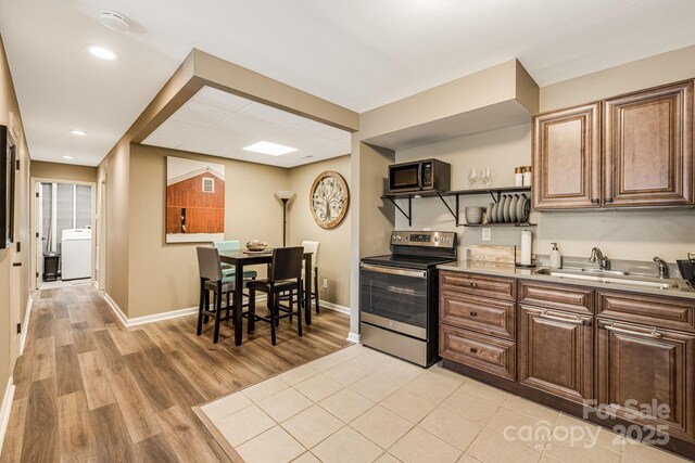 kitchen with a sink, open shelves, washer / clothes dryer, appliances with stainless steel finishes, and light countertops