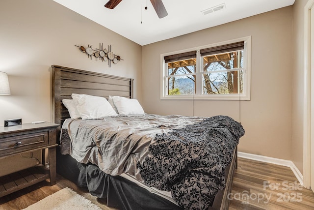 bedroom featuring a ceiling fan, wood finished floors, visible vents, and baseboards