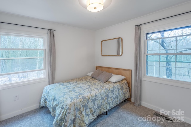 carpeted bedroom with visible vents, multiple windows, and baseboards