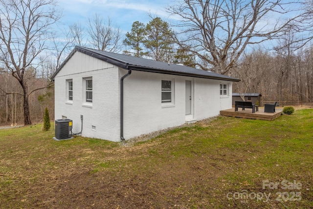 back of house featuring central AC, crawl space, a deck, a lawn, and brick siding