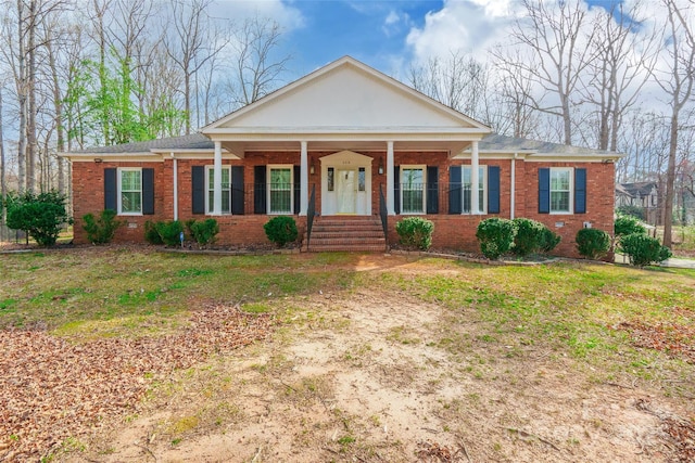 neoclassical / greek revival house featuring a front yard, covered porch, and brick siding