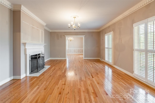 unfurnished living room with crown molding, a notable chandelier, baseboards, and light wood finished floors