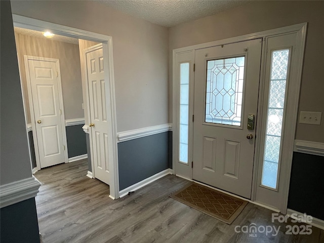 entryway featuring wood finished floors, a wealth of natural light, and a textured ceiling