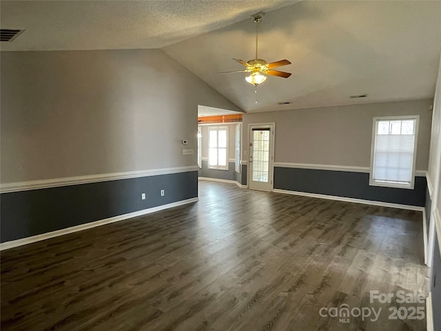 unfurnished room featuring visible vents, dark wood-style floors, baseboards, ceiling fan, and vaulted ceiling