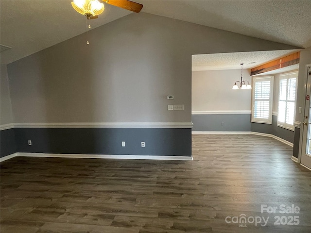 unfurnished room featuring baseboards, dark wood-style flooring, vaulted ceiling, a textured ceiling, and ceiling fan with notable chandelier