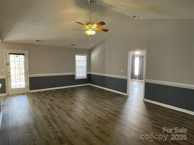 unfurnished room featuring dark wood finished floors, plenty of natural light, lofted ceiling, and visible vents