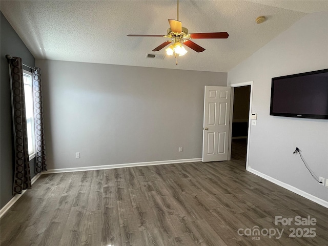 spare room with lofted ceiling, a textured ceiling, and dark wood finished floors