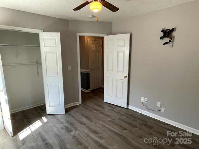 unfurnished bedroom with a closet, baseboards, a textured ceiling, and dark wood finished floors