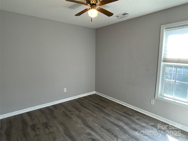 spare room with visible vents, dark wood-type flooring, a ceiling fan, a textured ceiling, and baseboards