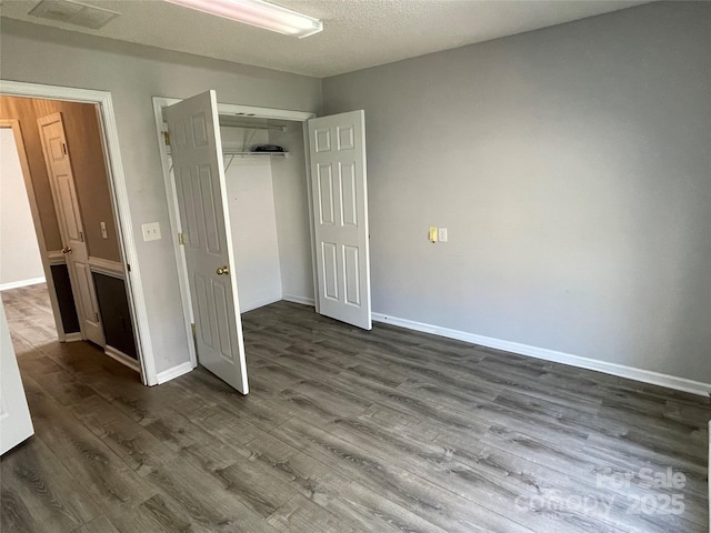 unfurnished bedroom with dark wood finished floors, baseboards, and a closet