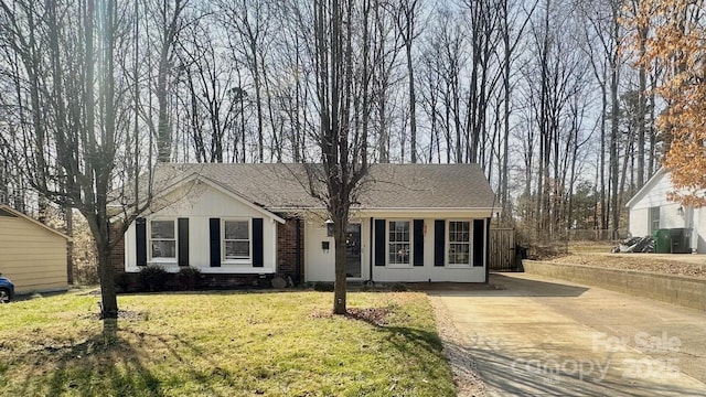 ranch-style home with driveway, brick siding, roof with shingles, and a front lawn