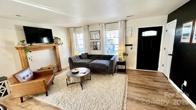 living area with wood finished floors, visible vents, and baseboards