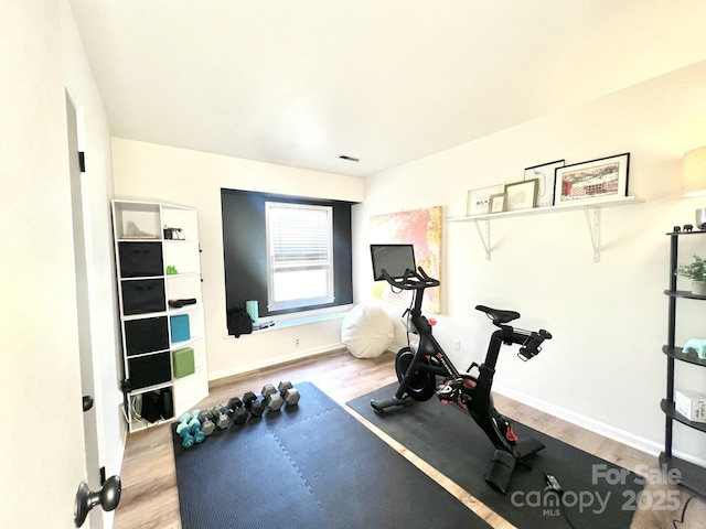 workout area featuring visible vents, baseboards, and wood finished floors