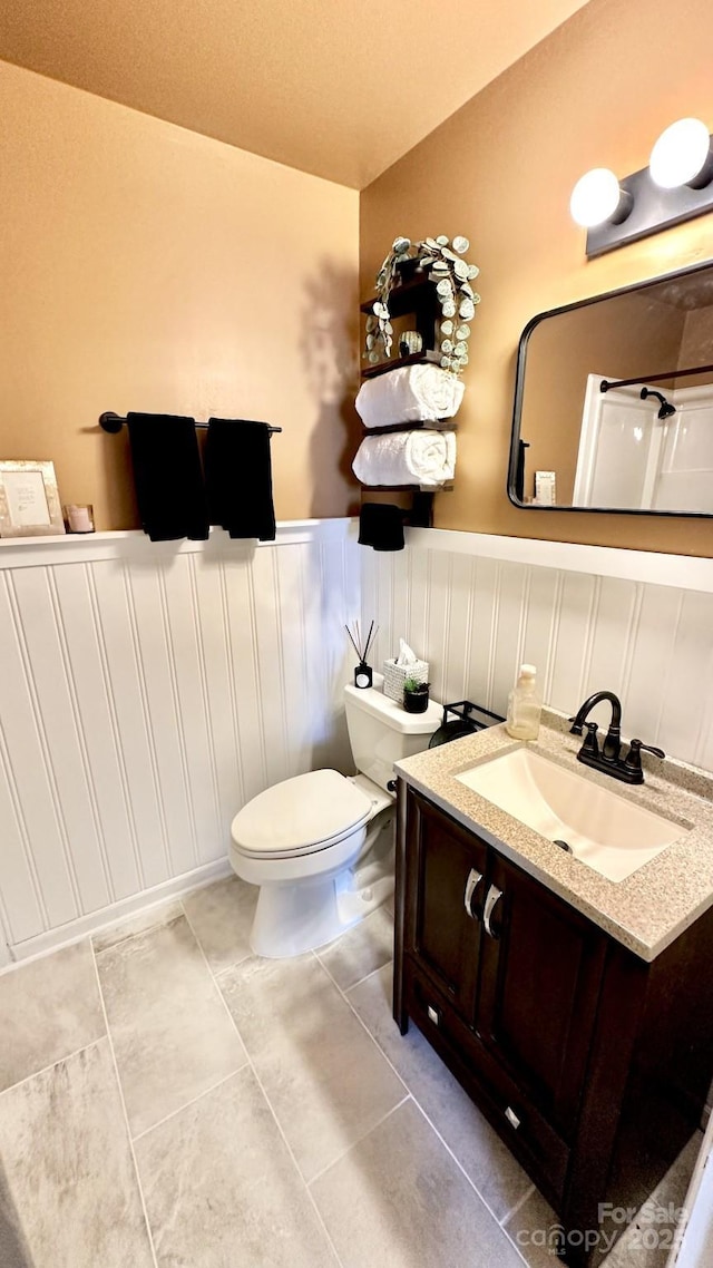 bathroom featuring tile patterned floors, a wainscoted wall, toilet, and vanity