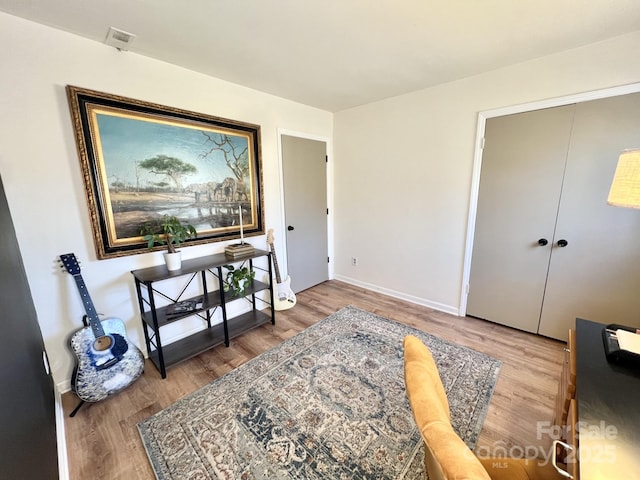 sitting room with baseboards and wood finished floors