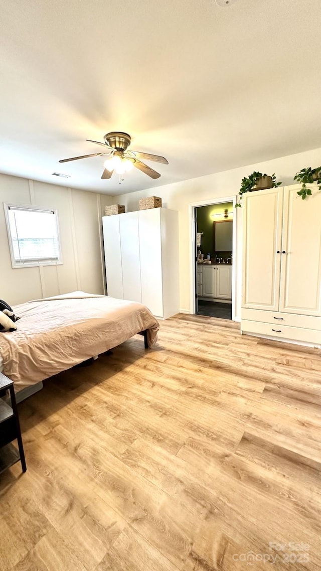 unfurnished bedroom featuring light wood-style floors, visible vents, ensuite bathroom, and ceiling fan