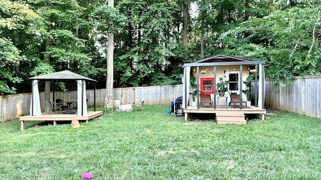 view of yard featuring a wooden deck, an outbuilding, and a fenced backyard