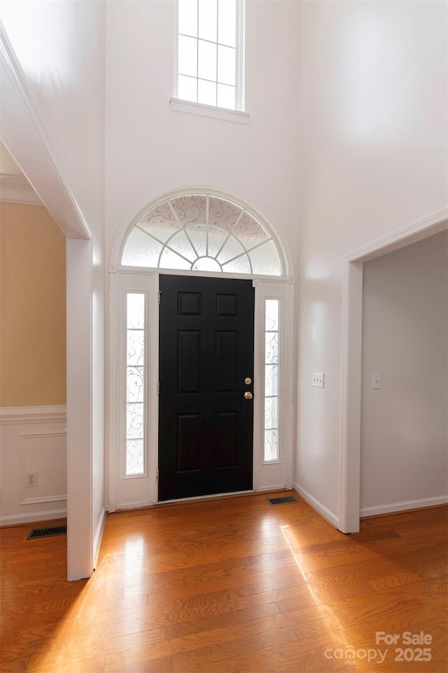 foyer with plenty of natural light, light wood-style flooring, a high ceiling, and visible vents