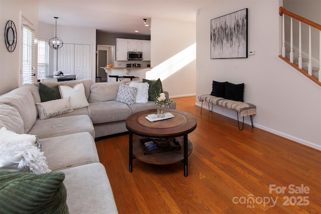 living room with stairway, wood finished floors, and baseboards