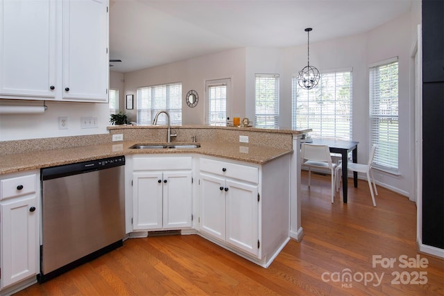 kitchen featuring a sink, dishwasher, a peninsula, and white cabinetry