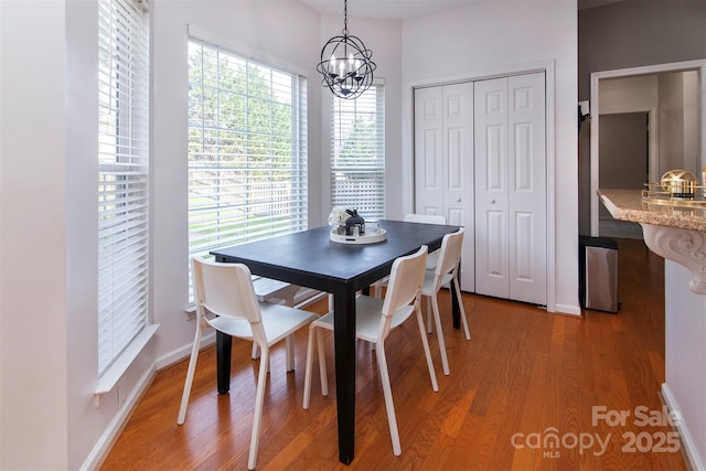 dining space with baseboards, an inviting chandelier, and light wood-style flooring