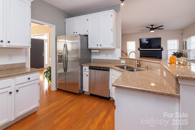 kitchen with a peninsula, ceiling fan, a sink, white cabinets, and appliances with stainless steel finishes