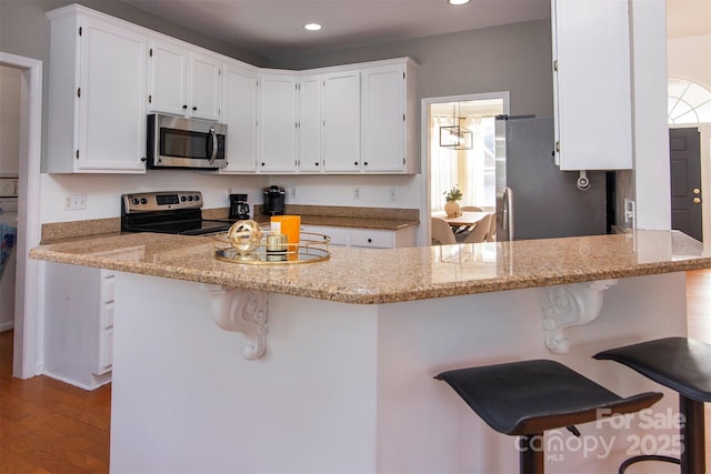 kitchen with white cabinetry, a peninsula, recessed lighting, and stainless steel appliances