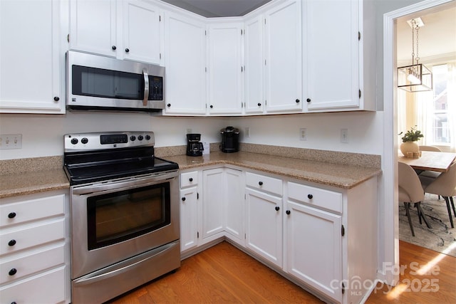 kitchen featuring appliances with stainless steel finishes, light wood-style flooring, and white cabinetry