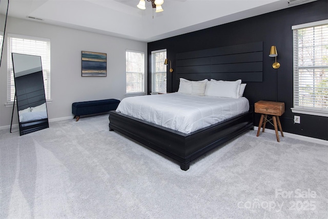 bedroom with visible vents, a ceiling fan, a tray ceiling, carpet floors, and baseboards