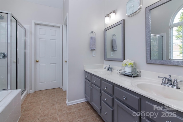 bathroom with tile patterned flooring, a shower stall, double vanity, and a sink