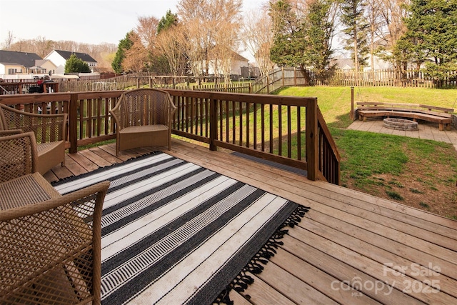 wooden deck featuring a fenced backyard, a lawn, and an outdoor fire pit