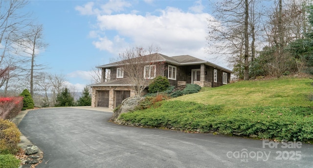 view of side of property with a garage, a lawn, and driveway