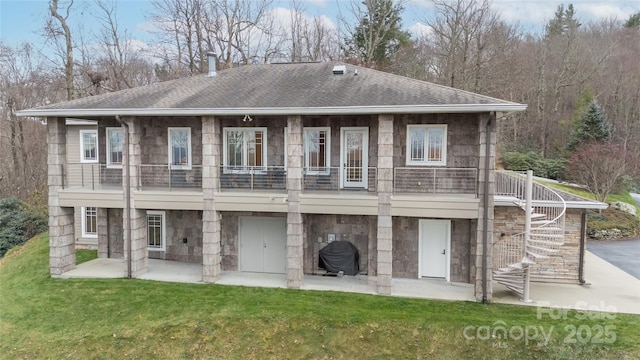 rear view of house with a shingled roof, stairs, stone siding, a patio area, and a lawn