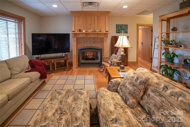 living room featuring visible vents, light wood-type flooring, recessed lighting, a tile fireplace, and a paneled ceiling