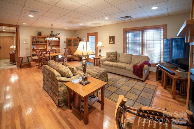 living room with a drop ceiling, recessed lighting, visible vents, and light wood finished floors