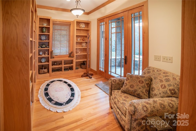 living area featuring french doors, crown molding, baseboards, and wood finished floors