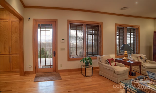 entryway featuring a healthy amount of sunlight, light wood-style floors, visible vents, and ornamental molding