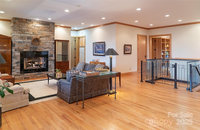 living area featuring wood finished floors, recessed lighting, a fireplace, crown molding, and baseboards