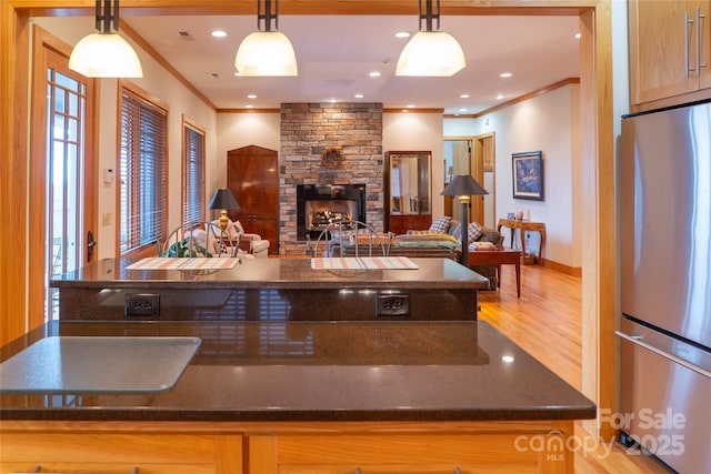 kitchen with crown molding, recessed lighting, a fireplace, freestanding refrigerator, and wood finished floors