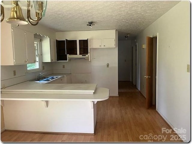 1327 Crestview Dr, Shelby, NC 28150 - kitchen featuring a peninsula, light wood-type flooring, light countertops, extractor fan, and a textured ceiling