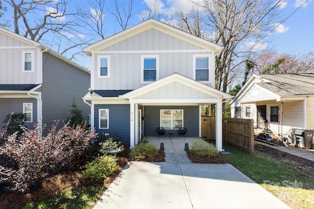 view of front of property with covered porch, board and batten siding, and fence