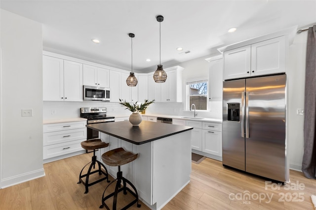 kitchen with light wood-style flooring, white cabinets, stainless steel appliances, and a sink