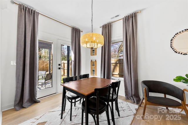 dining area featuring a notable chandelier, visible vents, light wood-type flooring, and baseboards