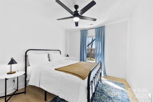 bedroom with visible vents, baseboards, a ceiling fan, and wood finished floors